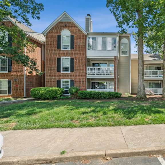 a row of houses with green lawns and trees at the timbers apartments, richmond, va, 23235