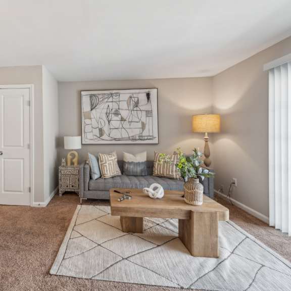 a living room with a grey sofa, a wooden coffee table, and a grey rug at staples mill townhomes apartments, richmond, va, 23228