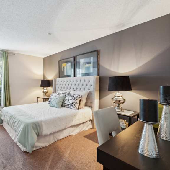 a bedroom with a large bed and a desk with a chair. at the timbers apartments, richmond, va, 23235