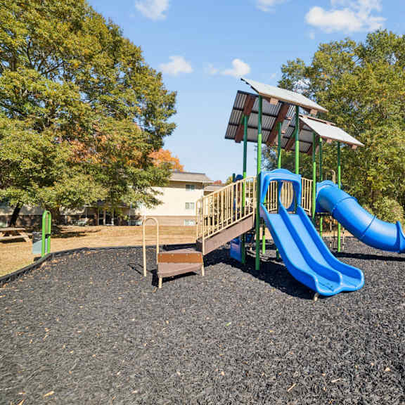 a playground with a blue slide and a green roofed structure at lakecrest apartments, prg real estate management, greenville, sc, 29615