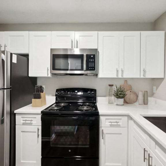 Thumbnail 4 of 7 a kitchen with black appliances and white cabinets and a stainless steel refrigerator