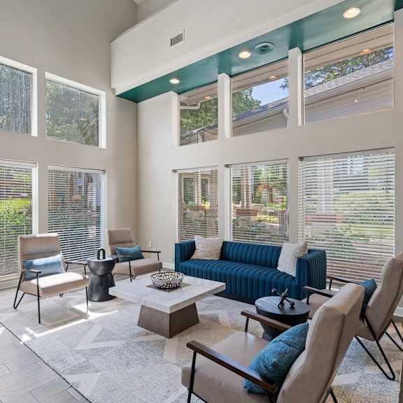 a seating area with a row of chairs and a wall of windows at the falls apartments in raleigh nc