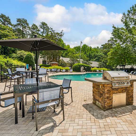 a backyard with a swimming pool and tables with umbrellas at lake johnson mews, raleigh, north carolina