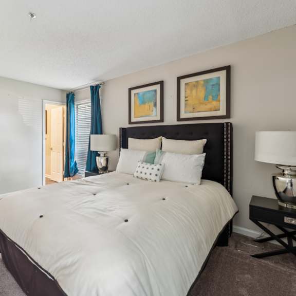 a bedroom with a large bed and a nightstand with a lamp. at the timbers apartments, richmond, virginia