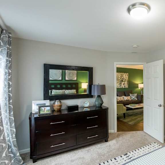 a bedroom with a dresser and mirror at the resort at lake crossing apartments, prg real estate, lexington, ky