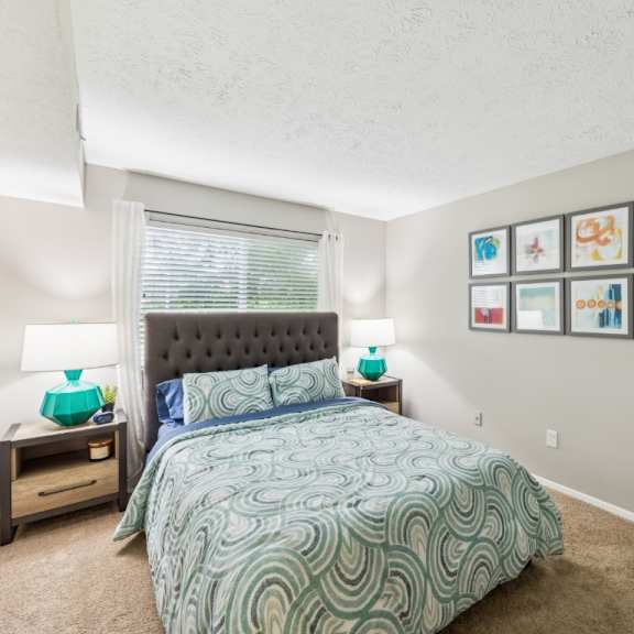 a bedroom with a bed, nightstands, and pictures on the wall at chinoe creek apartments, lexington
