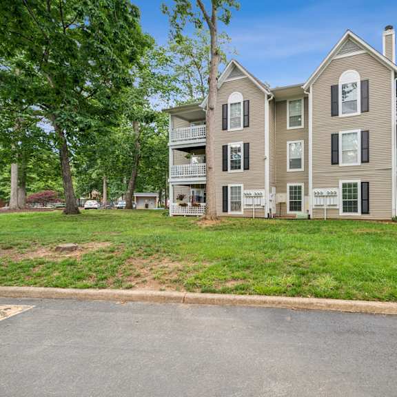 a large apartment building with a green lawn in front. at the timbers apartments, richmond, va