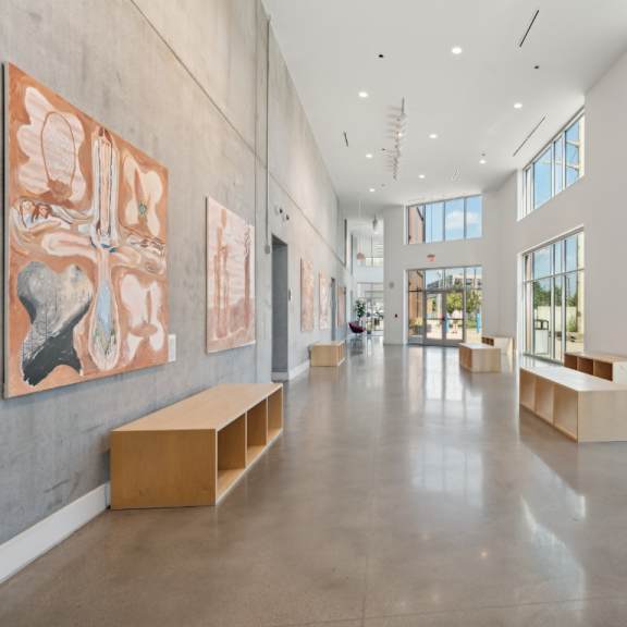 a spacious hallway with artwork on the walls and benches along the sides at south falls tower apartments, richmond