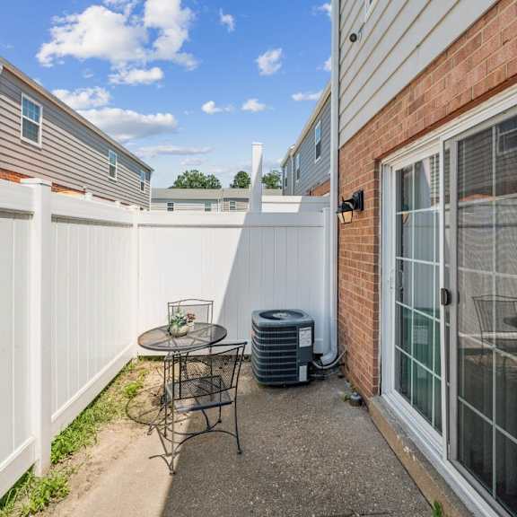 a patio with a table and chairs is surrounded by a white fence at staples mill townhomes apartments, richmond, va