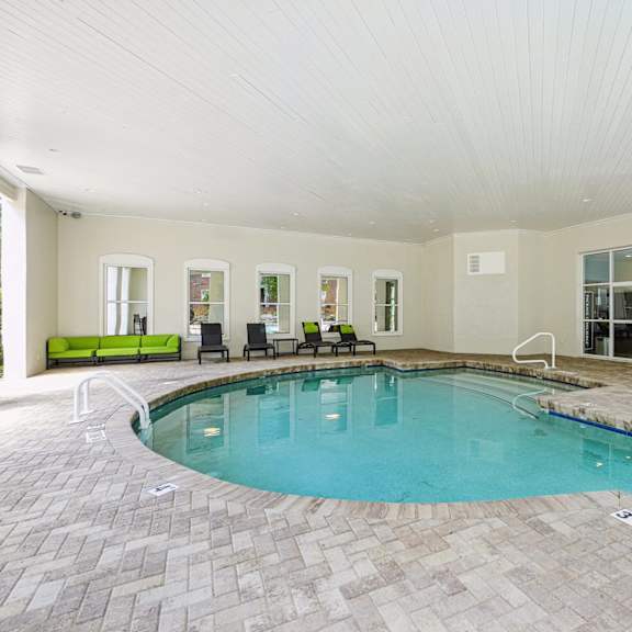 a large indoor swimming pool with a tiled floor and a bench at the falls apartments in raleigh nc