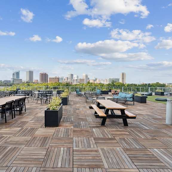 a wooden deck with benches and tables overlooking a city skyline at south falls tower apartments, richmond 23224