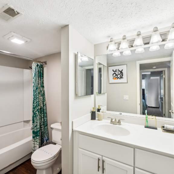 a white bathroom with a toilet, sink, and mirror at chinoe creek apartments, lexington, ky