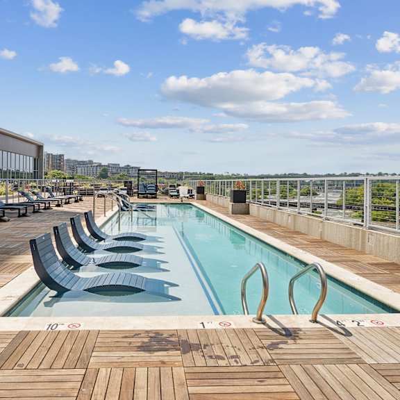 a large outdoor pool with wooden decking and lounge chairs at south falls tower apartments, richmond, va