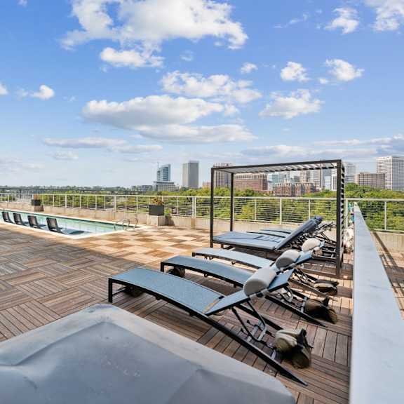 a rooftop patio with a table and chairs overlooking a city skyline at south falls tower apartments, virginia