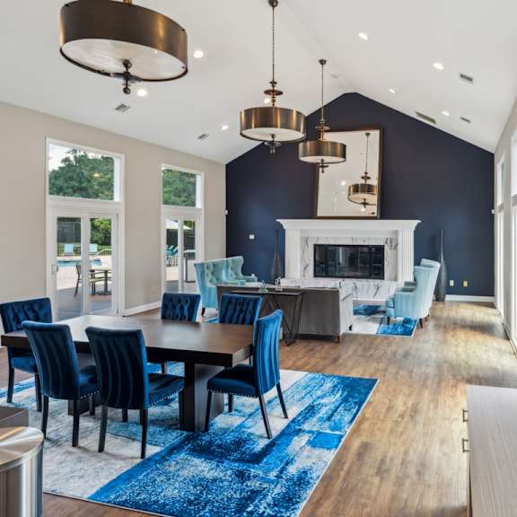 a modern dining room with a fireplace and blue chairs. at the timbers apartments, richmond 23235