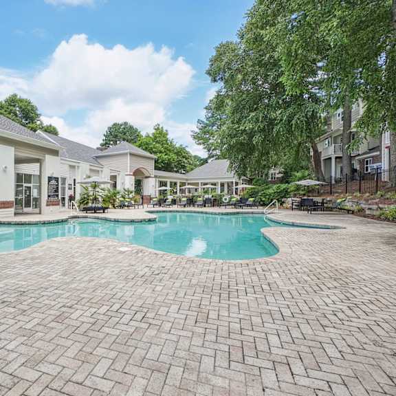 a large outdoor swimming pool surrounded by a brick patio at the falls apartments in raleigh nc