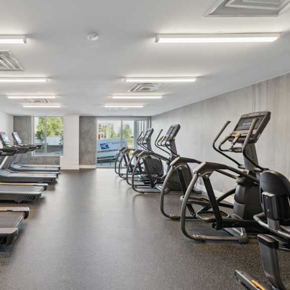 a gym with treadmills and elliptical machines at south falls tower apartments, virginia, 23224
