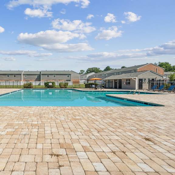 a large outdoor swimming pool surrounded by a brick patio at staples mill townhomes apartments, richmond 23228