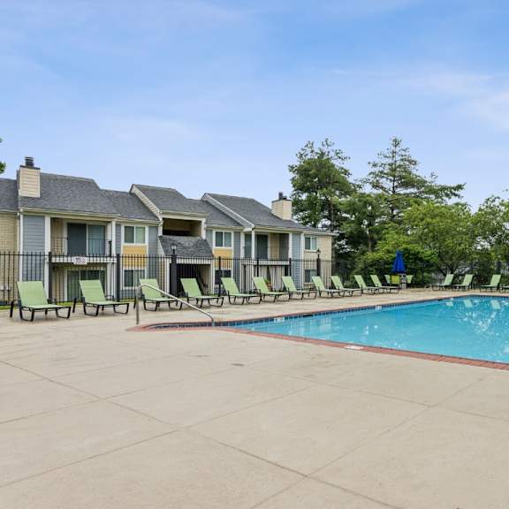 a swimming pool surrounded by lounge chairs and trees. at chinoe creek apartments, lexington, kentucky