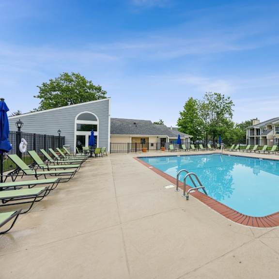 a large outdoor swimming pool surrounded by sun loungers and a building in the background at chinoe creek apartments, kentucky