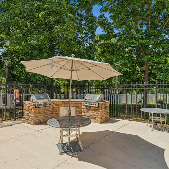 a patio with a table and chairs under an umbrella. at the timbers apartments, richmond, va, 23235