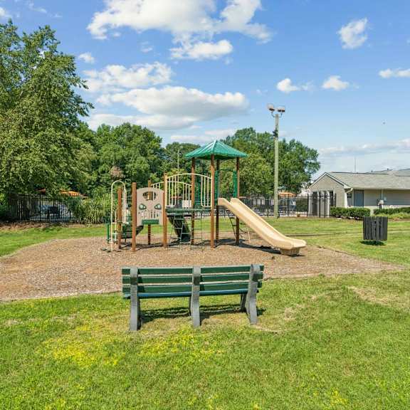 a playground with a green slide and two benches at staples mill townhomes apartments, richmond 23228