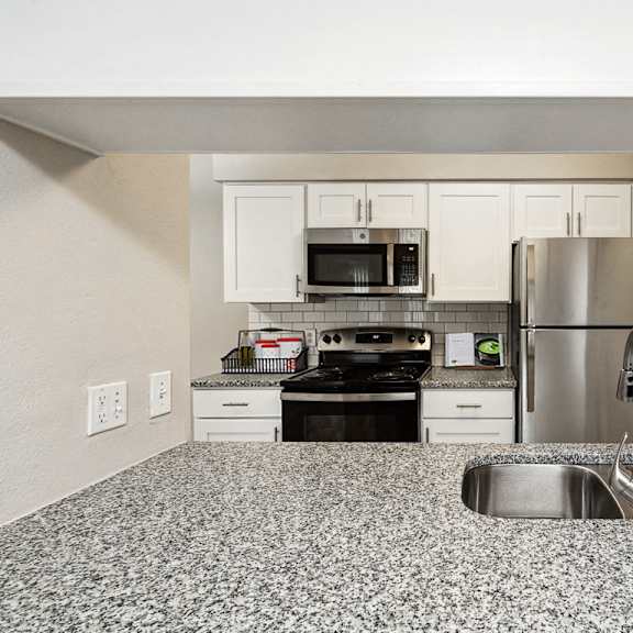 a kitchen with granite counter tops and stainless steel appliances at the reserve at barry apartments, kansas city