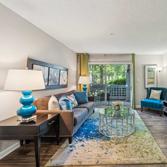 a living room with a blue rug and a glass table. at the timbers apartments, virginia