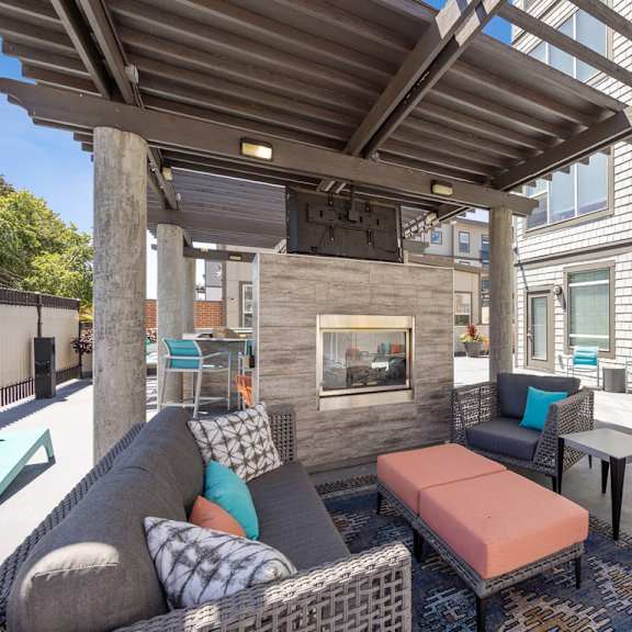 covered patio with couches and tables and a fireplace at 45 madison apartments, missouri, 64111