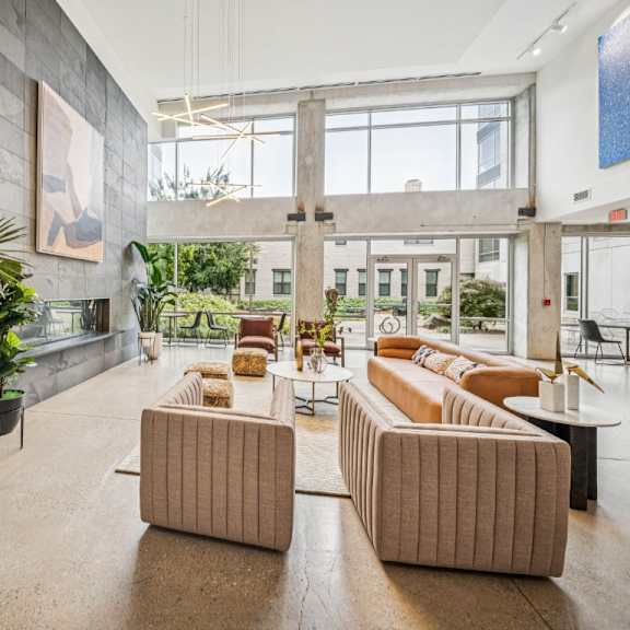 a spacious lobby with a large window, a potted plant, and two couches.