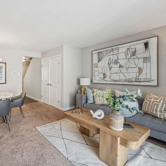a living room with a grey couch, a white table, and a painting on the wall at staples mill townhomes apartments, richmond, virginia