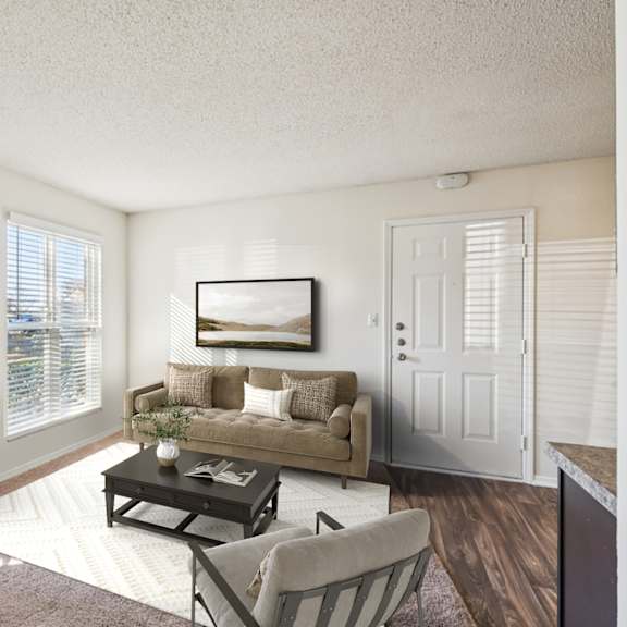 a living room with a couch, chair, and coffee table at the falls apartments in raleigh nc
