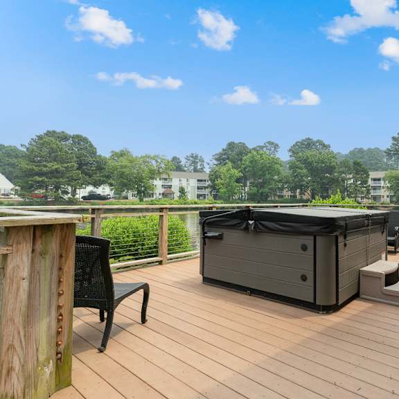 a hot tub on a deck with chairs and trees in the background at linkhorn bay apartments, virginia beach, va