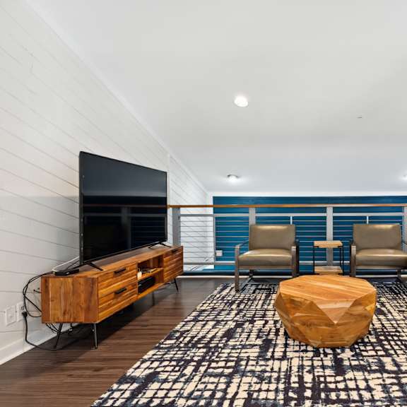 a living room with a leather couch and chairs and a flat screen tv on the wall at linkhorn bay apartments, virginia