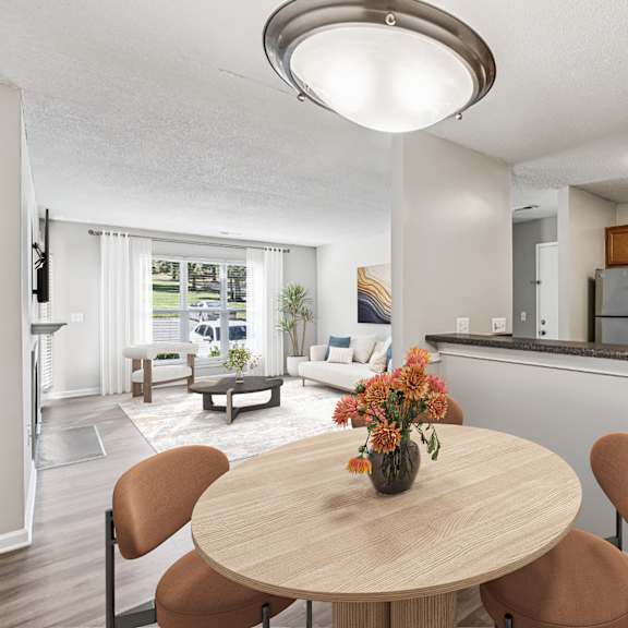 a kitchen with a table and chairs in the foreground and a living room in the background at park ridge estates, durham, 27713