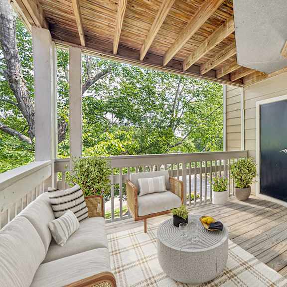 a wooden balcony with a couch, chair, and potted plants at beacon ridge apartments, prg real estate management, greenville, 29615