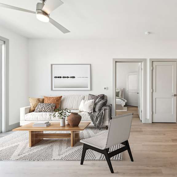 a modern living room with a white sofa, a wooden coffee table, and a black chair at the point apartments on 38th, norfolk, virginia