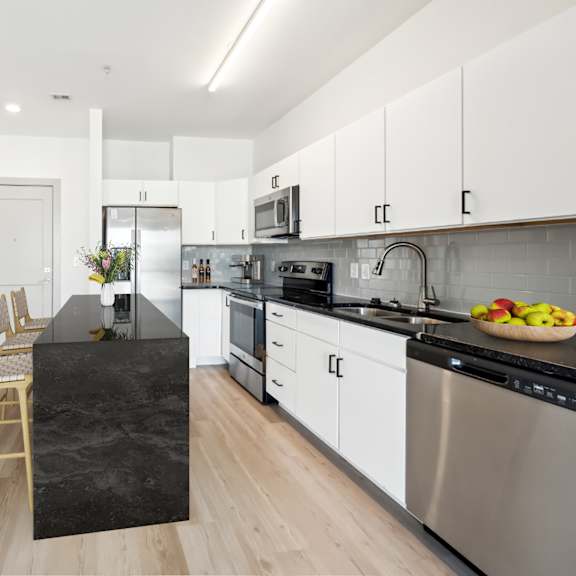 a modern kitchen with a black granite island and stainless steel appliances at the point apartments on 38th, norfolk, virginia