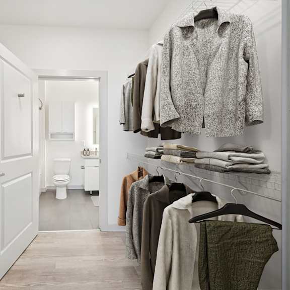 a walk in closet with clothes hanging and a toilet in the background at circ apartments, virginia