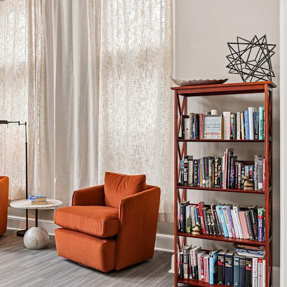 a living room with a bookshelf, two chairs, and a table.