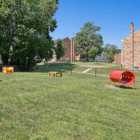 a playground with a red slide and a blue and yellow climbing frame.