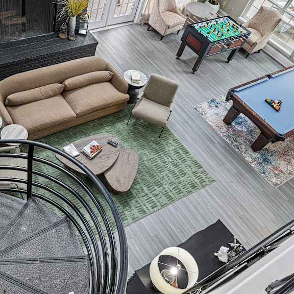 a living room with a pool table and a spiral staircase.