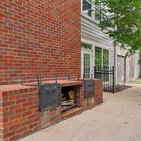 a brick wall with a fireplace and a tree in front of a house.