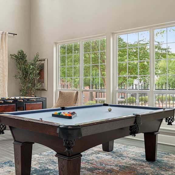 a pool table in a room with a chair and a plant.