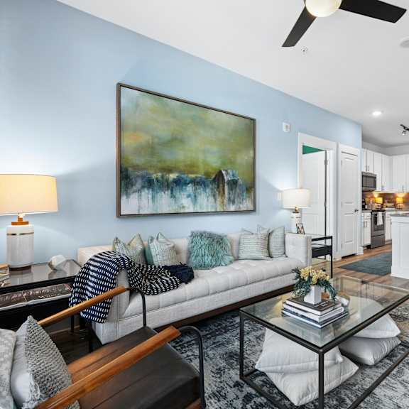 a living room with a white couch and a painting on the wall.