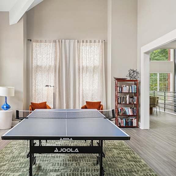 a joola table tennis table in a room with a sofa and a bookshelf.