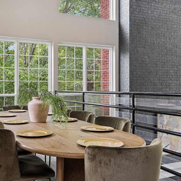a dining room with a table set for six with a view of trees outside.