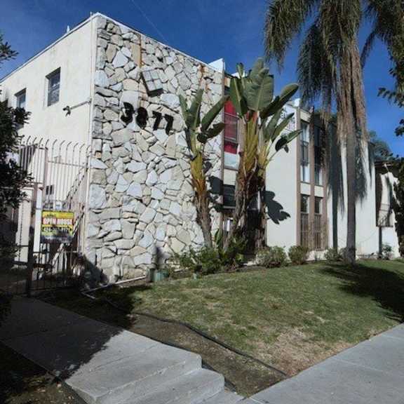a white building with a stone wall on the side.