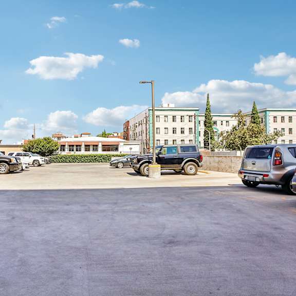 a parking lot with several cars and a building in the background.