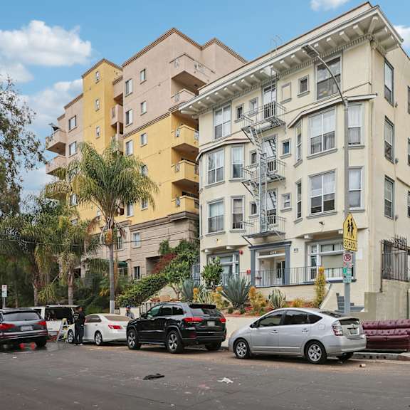 cars parked in front of a building with a yellow sign on the right.